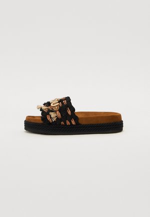 Black woven slide sandal with a brown suede footbed, featuring colorful tassel accents and a black woven sole.