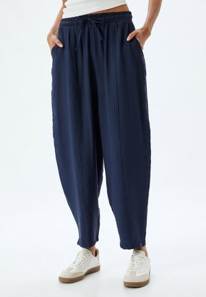 Pantaloni blu navy dalla vestibilità ampia, realizzati in tessuto morbido, con vita elasticizzata e tasche laterali, caratterizzati da una silhouette rilassata.