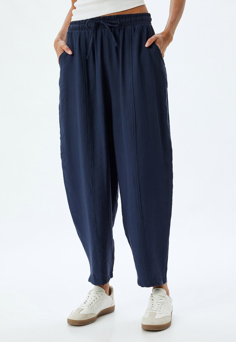 Lässig geschnittene navyblaue Hose aus weichem Stoff mit einem elastischen Bund und Seitentaschen, die eine entspannte Silhouette bietet.