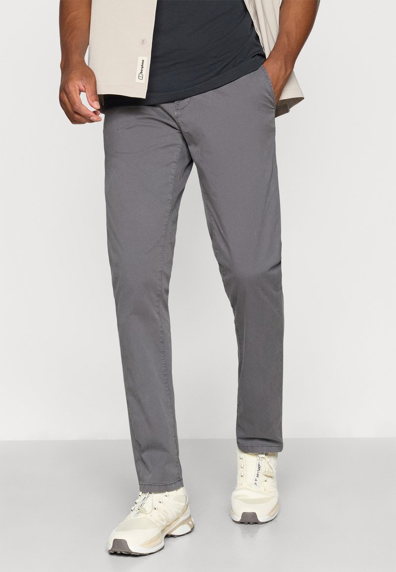 Graue, schlanke Hosen aus weichem Stoff mit glatter Textur. Getragen mit hellen Sneakers, die einen sauberen, modernen Stil zeigen.