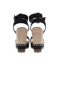 Černé espadrilové sandály na klínu s pletenou rýžovou podešví, kotníkovými pásky a kontrastním bílým prošitím. Hladká látková textura.