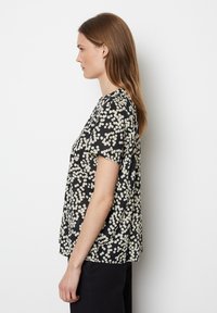 Schwarz Kurzarmpullover mit cremefarbenem Puntmuster, runder Halsauschnitt und lässiger Passform. Weicher Stoff mit glatter Textur.