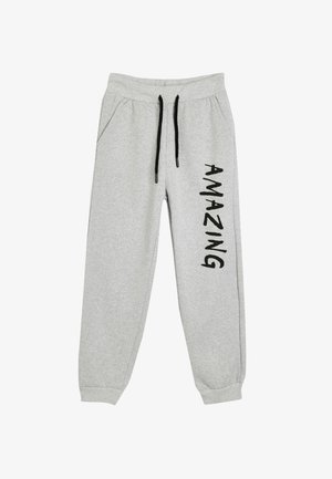 Graue Sweatpants mit schwarzem Kordelzug, seitlichen Taschen und "AMAZING" vertikal in fetten schwarzen Buchstaben aufgedruckt. Weiches Gewebe.