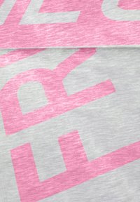 Lichtgrijze stof met grote, gedurfde roze tekst in een onregelmatig lettertype. De textuur is zacht, iets gemêleerd met een gladde afwerking.