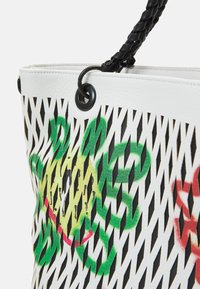Borsa tote bianca con motivo geometrico ritagliato, caratterizzata da design floreali verdi e gialli. Manico intrecciato nero e finiture nere.