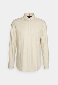 Beige langemouwen shirt gemaakt van zacht stof, met een knoopsluiting aan de voorkant, kraag en een borstzak aan de linkerkant. Rechte snit met standaard manchetten.
