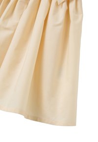 Gonna in cotone beige con un design arricciato, caratterizzata da una morbida texture e un orlo dritto. Il tessuto cade morbido con cuciture minime.