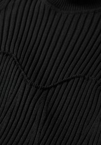 Maglione nero in tessuto a coste con pieghe verticali, superficie testurizzata e scollatura rotonda con finitura liscia.