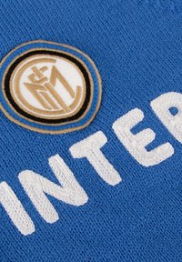Blauwe gebreide stof heeft een geborduurd logo in goud en zwart, met het woord "INTER" in gestructureerde witte letters.