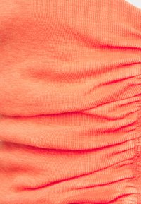 Tecido de coral em nervuras com uma textura franzida, exibindo elasticidade e uma composição suave. As fileiras de pregos criam um elemento de design fluido.