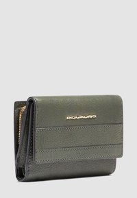Cartera de cuero texturizado verde oliva con cremallera dorada y logotipo "PIQUADRO" dorado en la solapa frontal, inclinada para mostrar detalles laterales.