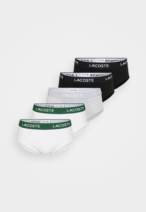 Five pairs of men's briefs in white, gray, black, and green, featuring a logoed waistband with "LACOSTE" printed prominently. Soft cotton fabric.
