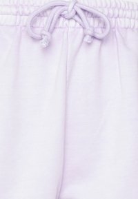 Svetle fialové tepláky vyrobené z měkké bavlny, s elastickým pasem a stahovací šňůrkou, a jemnou texturou. Žádné vzory nebo viditelné součásti.