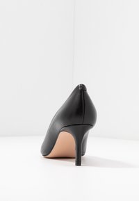 Scarpa nera in pelle con tacco alto a punta, tacco sottile a stiletto e superficie liscia. Presenta una soletta nuda e linee di design pulite.