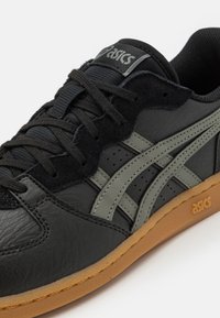 Scarpa in pelle nera con accenti grigi, dotata di una tomaia testurizzata, chiusura con lacci e suola in gomma. Logo del marchio sulla linguetta.