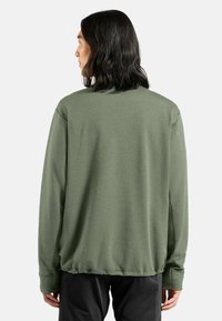 Grüner Langarmpullover mit lockerer Passform, gerippter Textur, rundem Ausschnitt und elastischem Bund. Die Rückansicht zeigt keine sichtbaren Logos oder Muster.