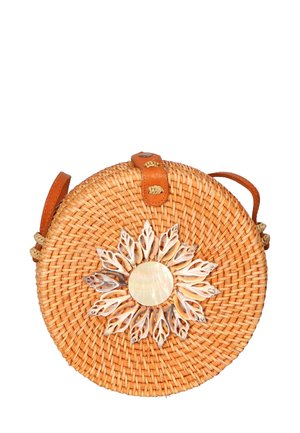 Round woven straw bag with a tan leather strap. Features a floral design made of seashells and a central circular shell accent.