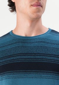 Blå og svart stripete strikkegenser med rund hals og teksturert stoffmønster, med en tettsittende design.