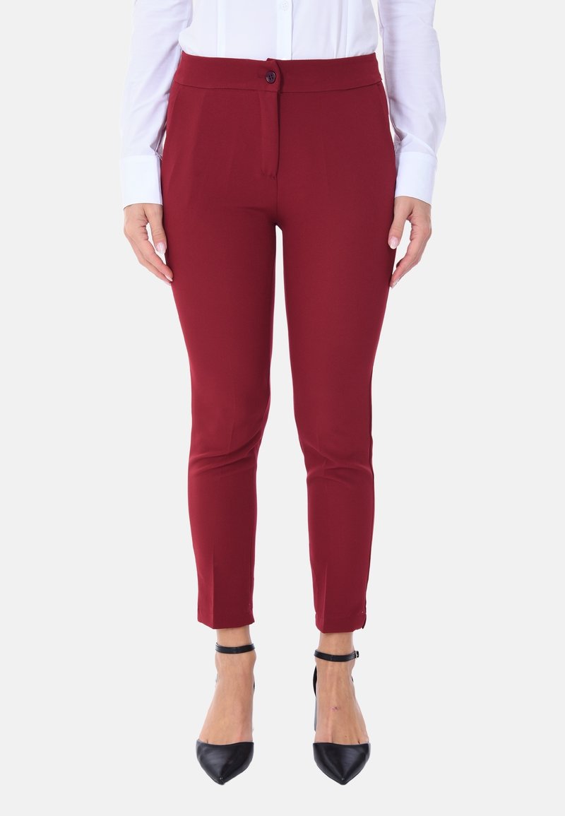 Pantaloni su misura color bordeaux realizzati in un tessuto liscio e stretch, con gamba affusolata, chiusura frontale con bottone e lunghezza alla caviglia, abbinati a tacchi a spillo neri.