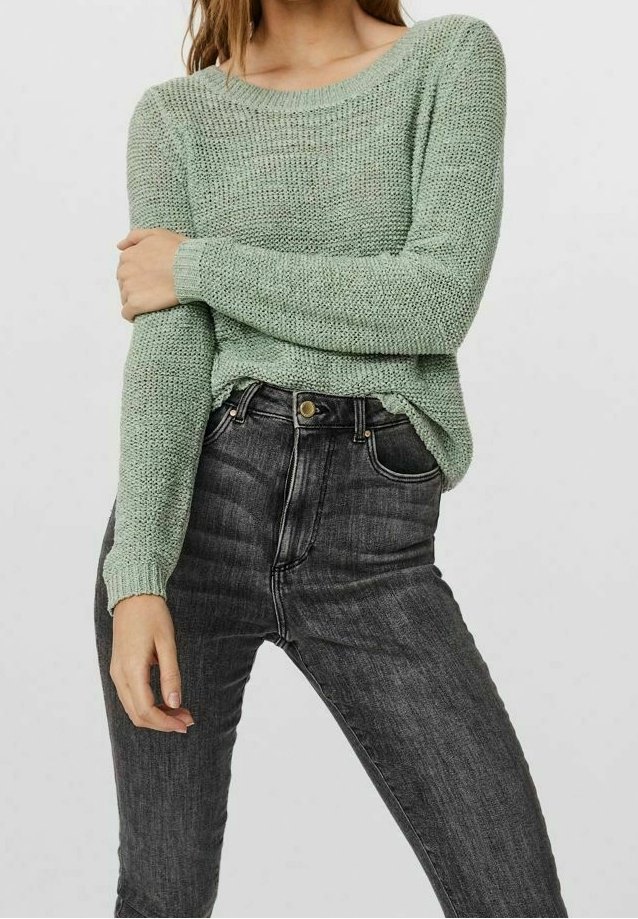 Maglione lavorato a maglia verde chiaro con una vestibilità ampia, scollo rotondo e maniche lunghe, abbinato a jeans neri a vita alta.