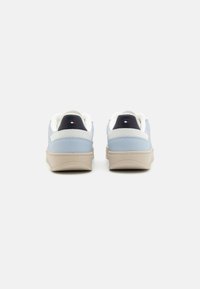 Baskets bleu clair avec une finition texturée, accents blancs, semelle beige et languette de talon noire avec un petit logo.