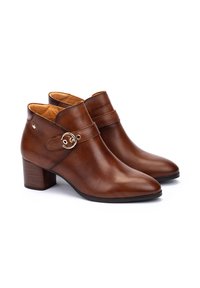 Botas de cuero marrón hasta el tobillo con puntera afilada, tacón medio en bloque, correa lateral y detalle decorativo de hardware dorado. Textura suave y diseño minimalista.