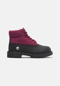 Botines negros y burdeos con un upper de cuero impermeable, punta redonda, suela de goma plana y costuras en contraste. Presenta el logo en el lateral.
