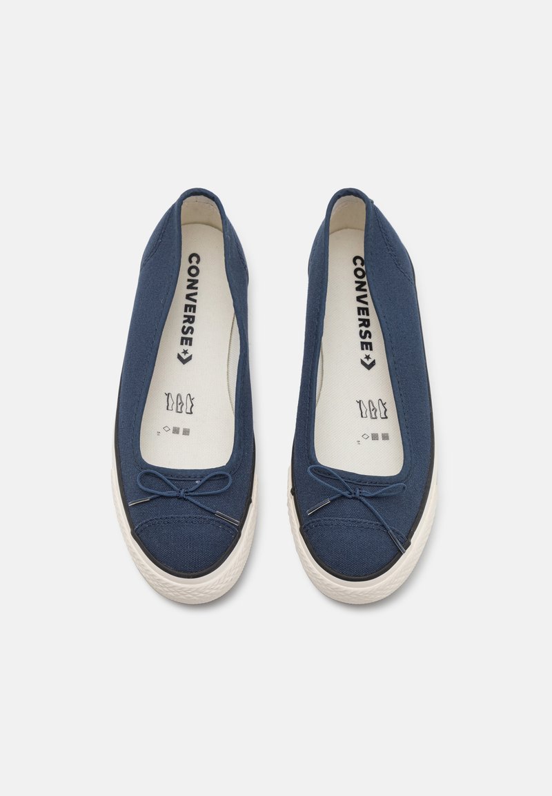 Marineblaue Leinenschlupfschuhe mit runder Zehenform, kontrastierender weißer Gummisohle und dekorativem Schleifendetail an der Vorderseite.