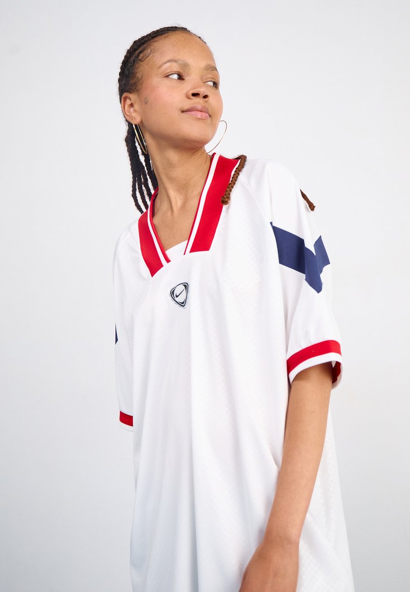 Weißes Kurzarmtrikot mit roten und blauen Akzenten. V-Ausschnitt-Design mit einem Logo in der Mitte. Aus strukturiertem, atmungsaktivem Material gefertigt.
