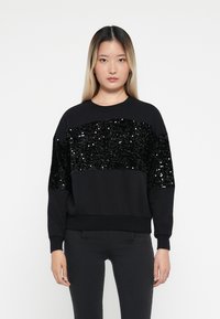 Sweatshirt preto com um painel horizontal de lantejoulas no peito, com um corte descontraído e punhos canelados. Material suave e design elegante.