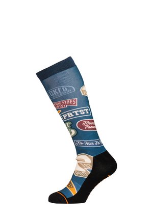 Blauwe kniekous met zwarte hiel en teen, met kleurrijke vintage-stijl patches en tekstzinnen zoals "PETST" en "Mountain Pioneers."