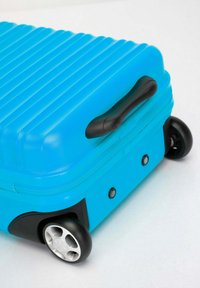 Tvrdý kufr jasně modré barvy vyrobený z plastu s texturovanými drážkami, černou rukojetí a multidirigujícími koly pro snadnou mobilitu.