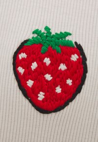 Diseño de fresa bordada que presenta frutas rojas con semillas blancas y hojas verdes, delineadas en negro, sobre un fondo de tela clara y acanalada.