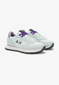 Sneakers azzurri chiari realizzati in suede e mesh, con lacci viola e un logo nero sulla linguetta. La suola è bianca con una base nera.
