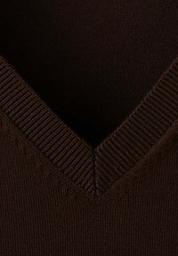Gros plan d'un pull en maille marron foncé à col en V avec détails côtelés au col.