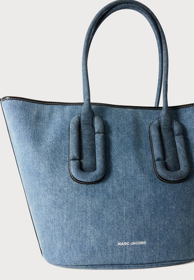 Μπλε τσάντα tote από τζιν Marc Jacobs με στρογγυλεμένες διπλές λαβές και μαύρο περίγραμμα σε ανοιχτό φόντο.