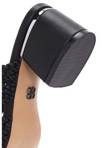 Scarpa piatta nera con tacco arrotondato, texture intrecciata sulla parte superiore e suola in gomma con scanalature orizzontali per una migliore aderenza.