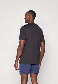 Sort kortærmet t-shirt med rund hals, fremstillet af et glat materiale, med en afslappet pasform og subtile stikningsdetaljer på skuldrene.