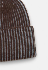 Cappello lavorato a maglia con strisce verticali marroni e azzurro chiaro. Realizzato in lana morbida e morbida. Presenta un orlo ripiegato nella parte inferiore.