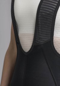 Black bodysuit featuring mesh panels in a V shape. Textured black straps and stitching visible, highlighting breathable design.