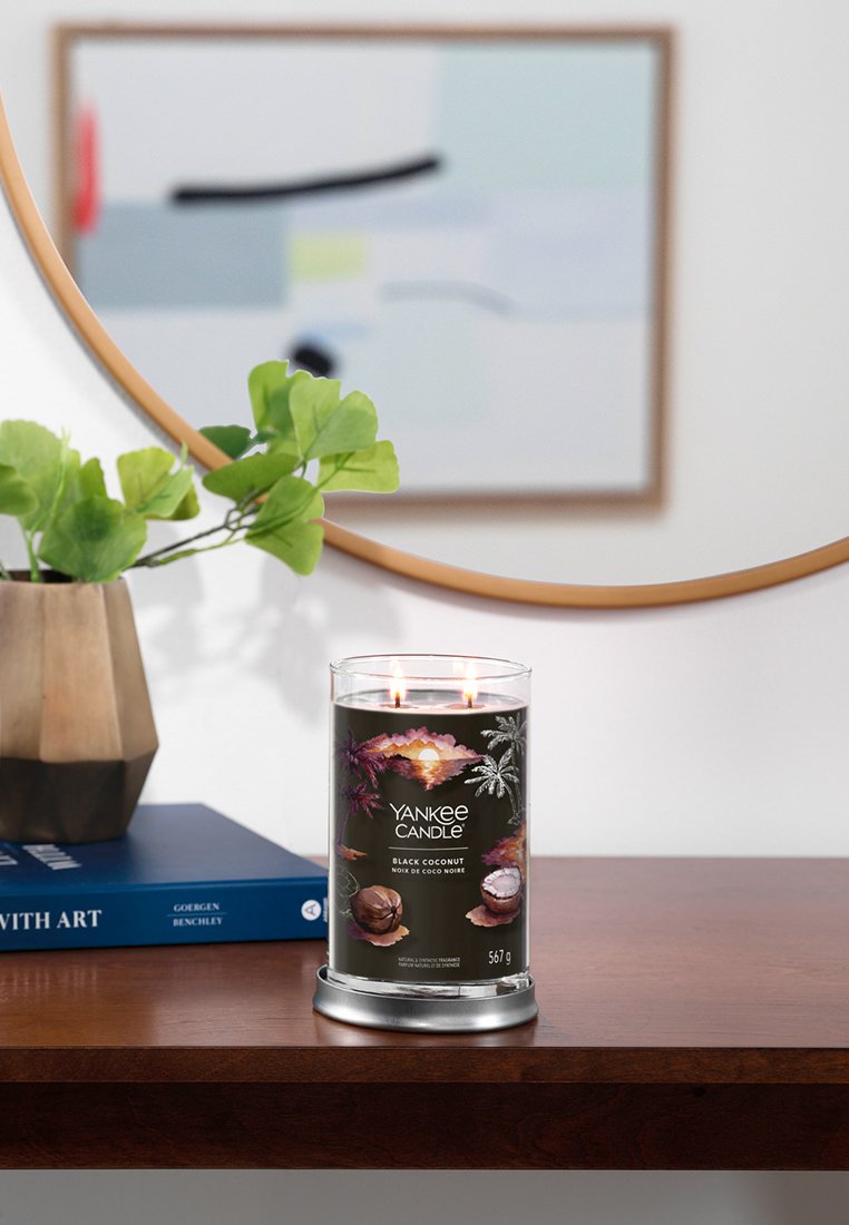 Yankee Candle, Black Coconut, in einem klaren Glasbehälter mit zwei Dochten, zeigt eine dunkle Wachsfarbe und einen metallischen silbernen Halter auf einem Holztisch.