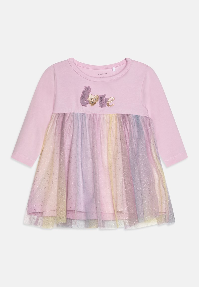 Rozā garas piedurknes kleita ar mīkstu augšdaļu un slāņotu mirdzošu tule svārku pasteļa krāsās. Iezīmē "mīlestība" aplikāciju ar sirds detaļu.