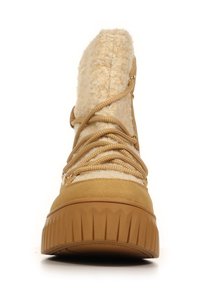 Beige winterboot met dikke rubberen zool, fuzzy bovenstof en tan kleurige veters die kruislings aan de voorkant zijn bevestigd.