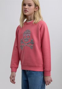 Pink sweatshirt with a colorful skull and crossbones graphic, ribbed crew neckline, and cuffs. Soft material and relaxed fit.