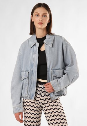 Helle blaue Jeansjacke mit entspannter Passform, ausgestattet mit einem Kragen, zwei Vordertaschen und kombiniert mit Hosen im strukturierten Zickzackmuster.