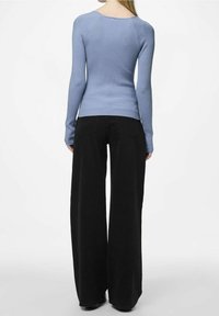 Haut à manches longues côtelé de couleur bleu clair, silhouette ajustée. Associé à un pantalon noir à jambes larges avec poches arrière et texture de tissu lisse.