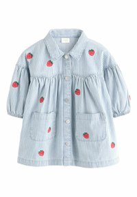 Gestreifte Bluse in Blau und Weiß mit kurzen Puffärmeln, die mit Erdbeerstickereien verziert ist und zwei frontalen Taschen verfügt. Silberne Knöpfe entlang der Mitte.