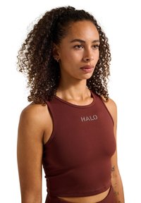 Brun idrotts crop top med en åtsittande design, utrustad med hög krage och silverfärgad "HALO"-logotyp. Tillverkad av ett mjukt, elastiskt tyg.
