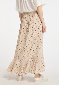 Gonna maxi beige con motivo floreale, vita elasticizzata, orlo arricciato e tessuto morbido. Indossata con sneakers bianche.
