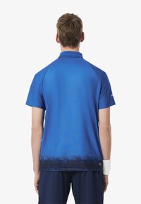 Kortärmad blå polo skjorta med en gradientdesign, mjuk tygtextur och krage, visad bakifrån med minimal detaljering.